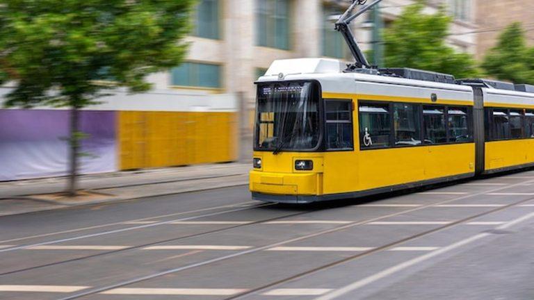 חשמלית צהובה בתנועה ברחוב עיר - סמל התחבורה הציבורית והמוניות בסרייבו בוסניה